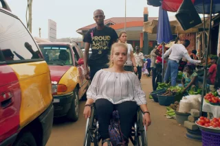 Junge Frau im Rollstuhl auf einem Markt in Ghana.