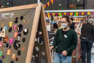 Eine junge Frau spielt ein Geschicklichkeitsspiel auf einer Messe.