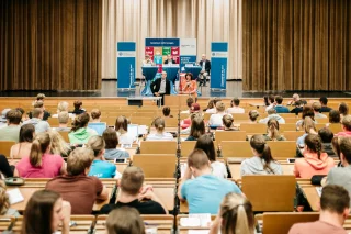 Studierende sitzen in einem Hörsaal und schauen nach vorne.