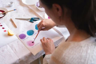Eine Person malt mit Wasserfarbe unterschiedliche Farbkreise auf ein Blatt.